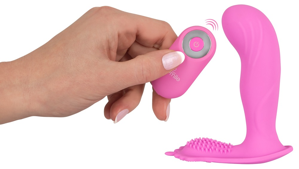 Eine Hand hält eine kleine rosa Fernbedienung neben einem rosa Silikon-Sexspielzeug vor weißem Hintergrund.