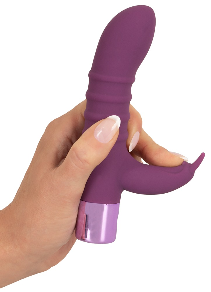 Eine Hand hält ein violettes, gewelltes Wellness-Gerät mit einer Metallbasis.
