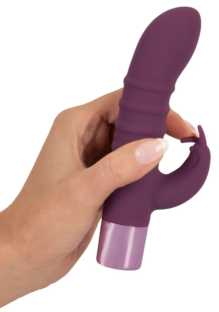 Eine Hand hält ein violettes, gewelltes Adult-Toy vor einem weißen Hintergrund.