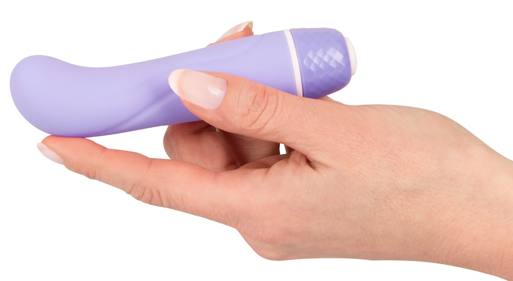 Eine Hand hält ein lavendelfarbenes, geschwungenes Wellness-Gerät mit einer strukturierten Kappe gegen einen weißen Hintergrund.