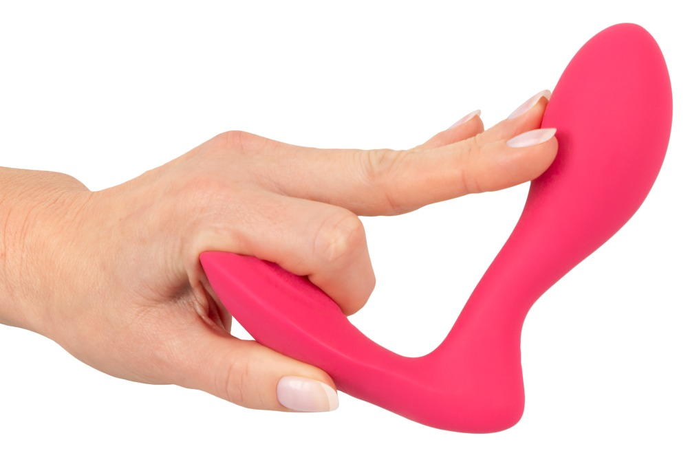 Eine Hand hält einen geschwungenen, pinkfarbenen Silikonvibrator vor weißem Hintergrund.