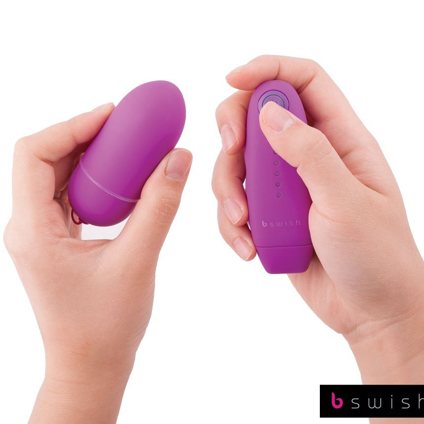 Manos sosteniendo un dispositivo morado en forma de huevo con botones y logo bswish en fondo blanco.