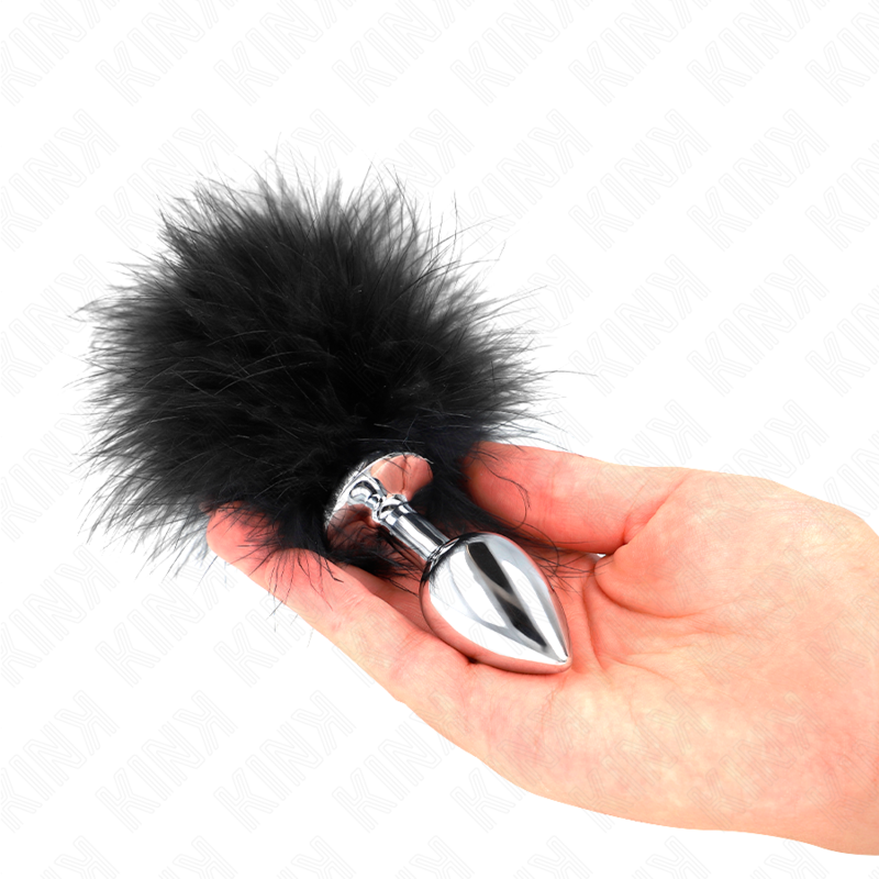 Una mano sostiene un tapón plateado con un gran pompón de plumas negras esponjosas en la base sobre fondo blanco.
