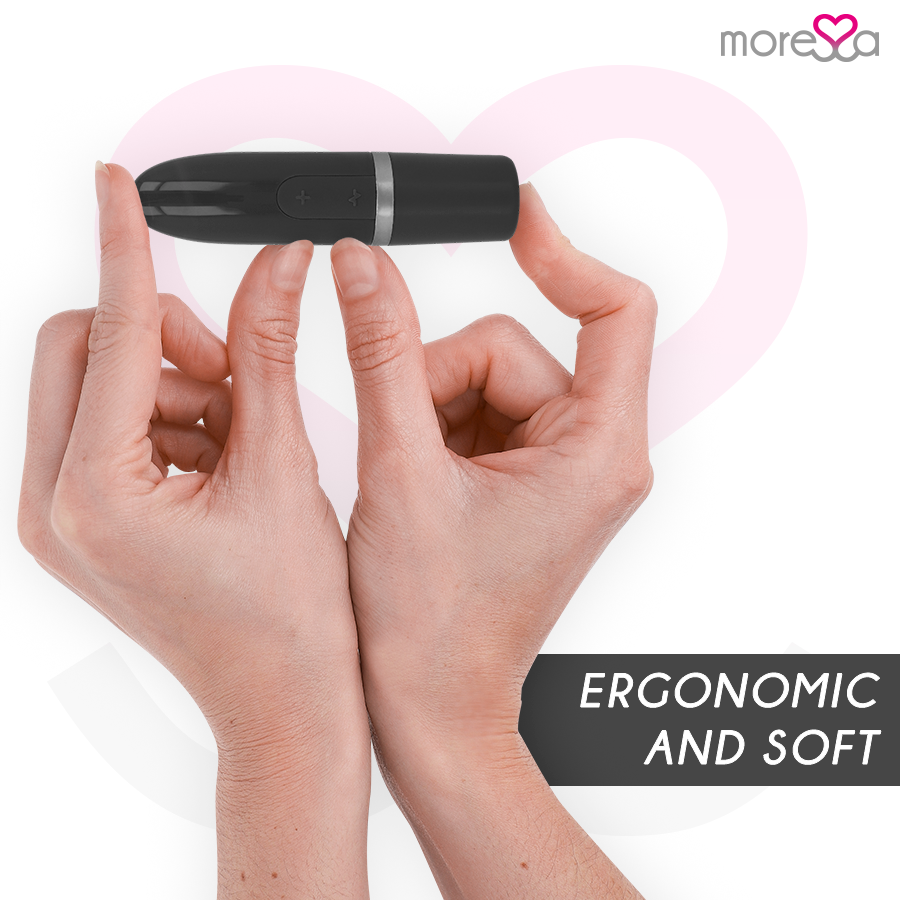 Dos manos sostienen un dispositivo de bienestar negro y ergonómico sobre un fondo de corazón rosa.