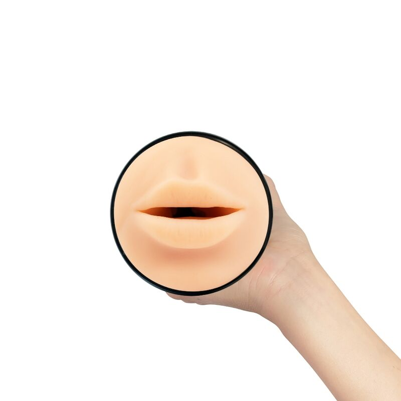 Una mano sostiene un objeto redondo del color de la piel con labios esculpidos y una abertura sobre fondo blanco.