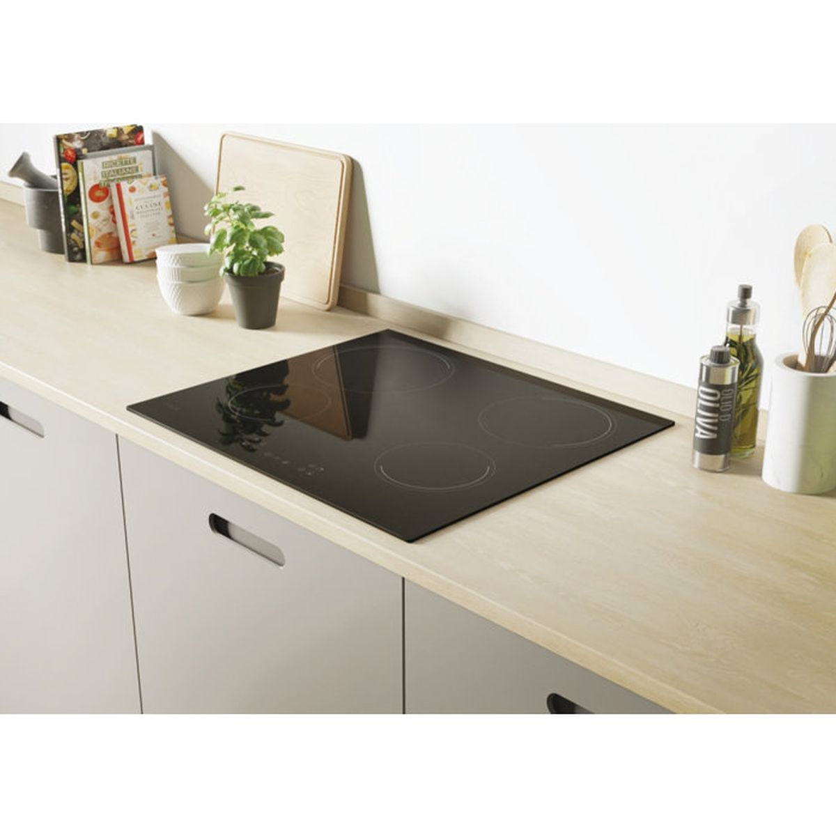 Una placa de inducción negra sobre una encimera de madera en una cocina moderna con libros de cocina y hierbas.