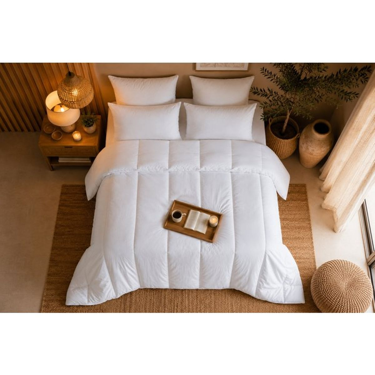 Ein weißes Bett in einem gemütlichen Schlafzimmer mit Holzakzenten, Pflanzen und einem Tablett mit Buch.