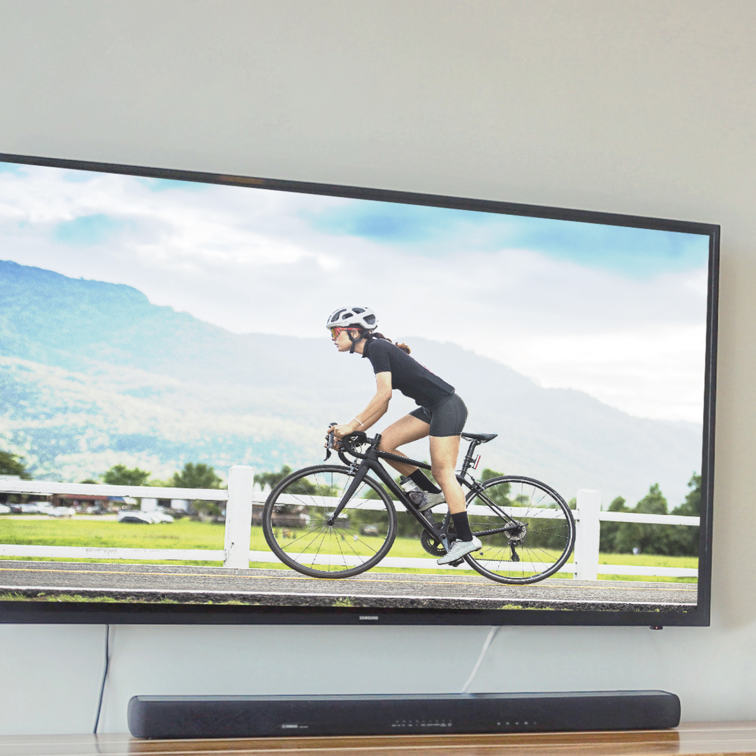 Una TV a parete mostra una donna in bicicletta con le montagne sullo sfondo.