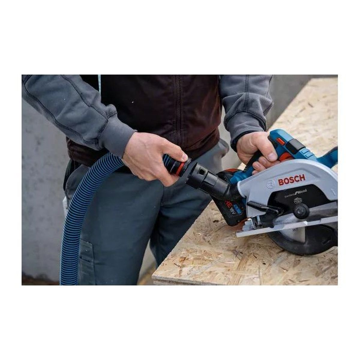 Un trabajador conecta una manguera azul a una sierra circular Bosch inalámbrica en una tabla de madera.