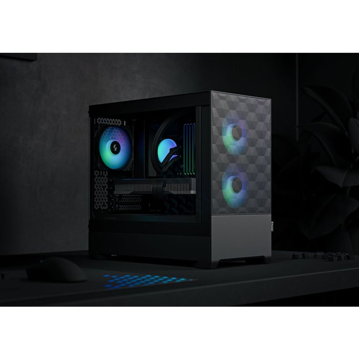Ein schwarzer PC-Gaming-Tower mit RGB-Lüften und geometrischer Frontplatte auf einem dunklen Schreibtisch.