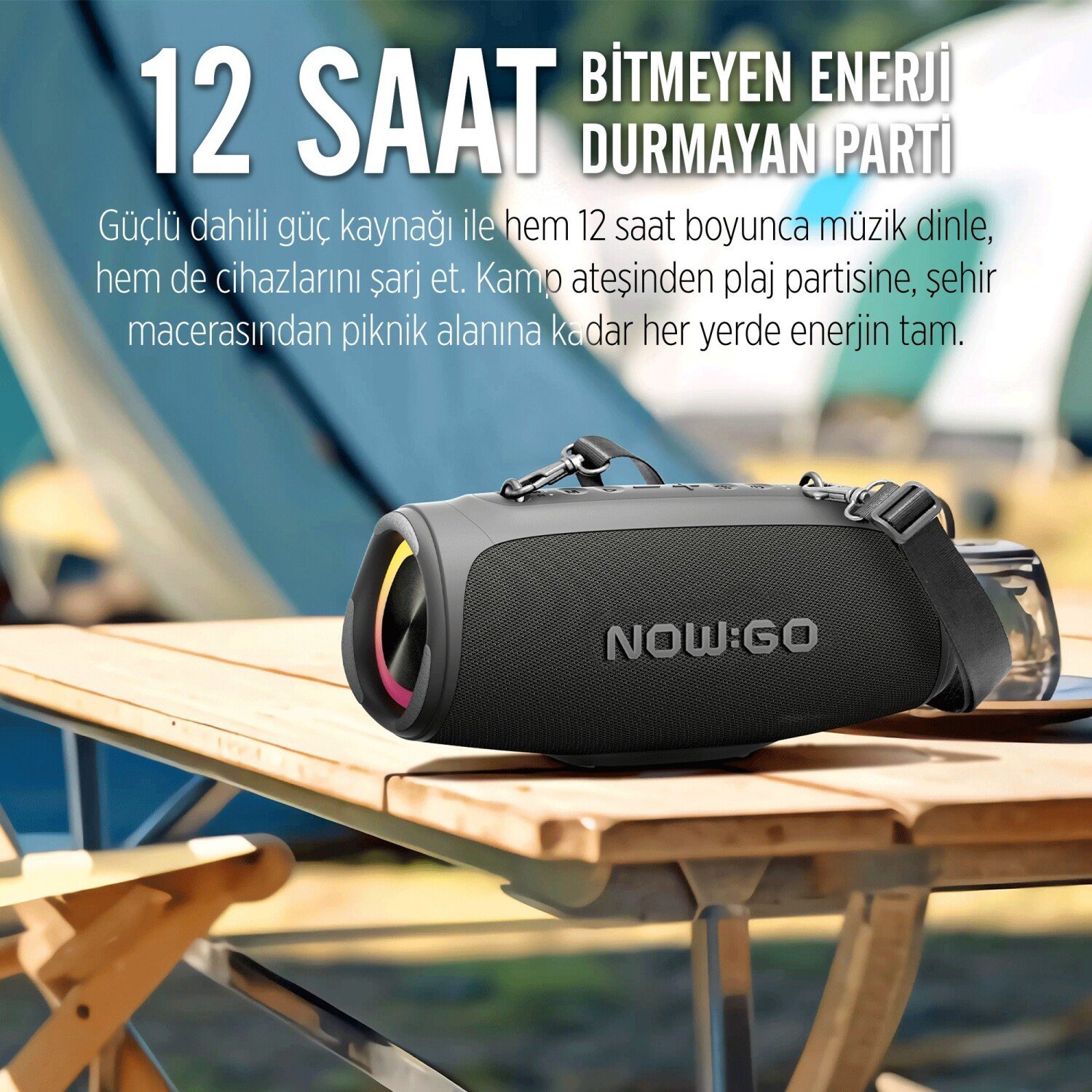 Czarny głośnik Bluetooth NOW:GO na drewnianym stoisku na zewnątrz z tekstem powyżej.