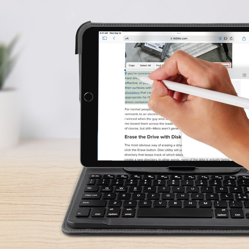 Una mano usa un lápiz óptico en un iPad con funda de teclado, resaltando texto.