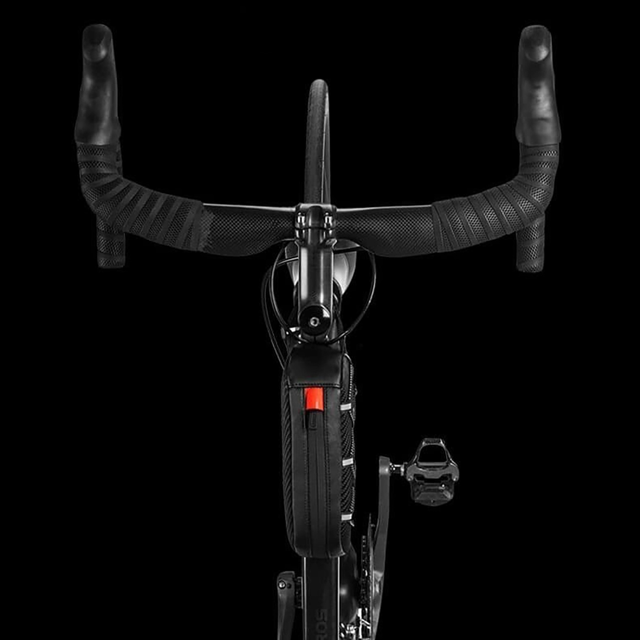 Primo piano di un manubrio di bicicletta con telaio nero e borsa frontale su sfondo nero.