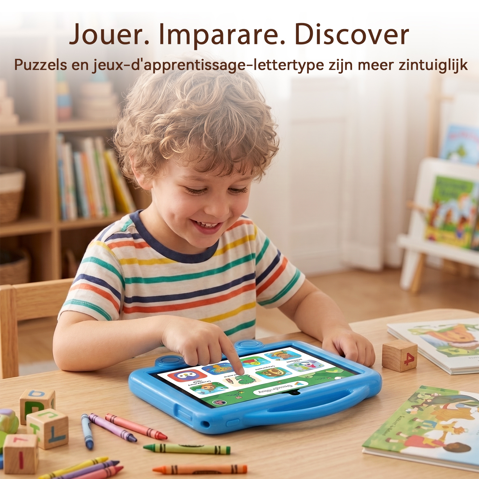 A young boy smiling while touching a blue tablet screen, with toys and books on the wooden table around him.