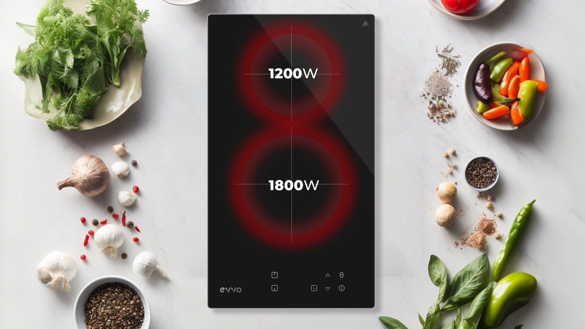 Placa de inducción negra con dos zonas de cocción, rodeada de ingredientes frescos sobre mármol blanco.