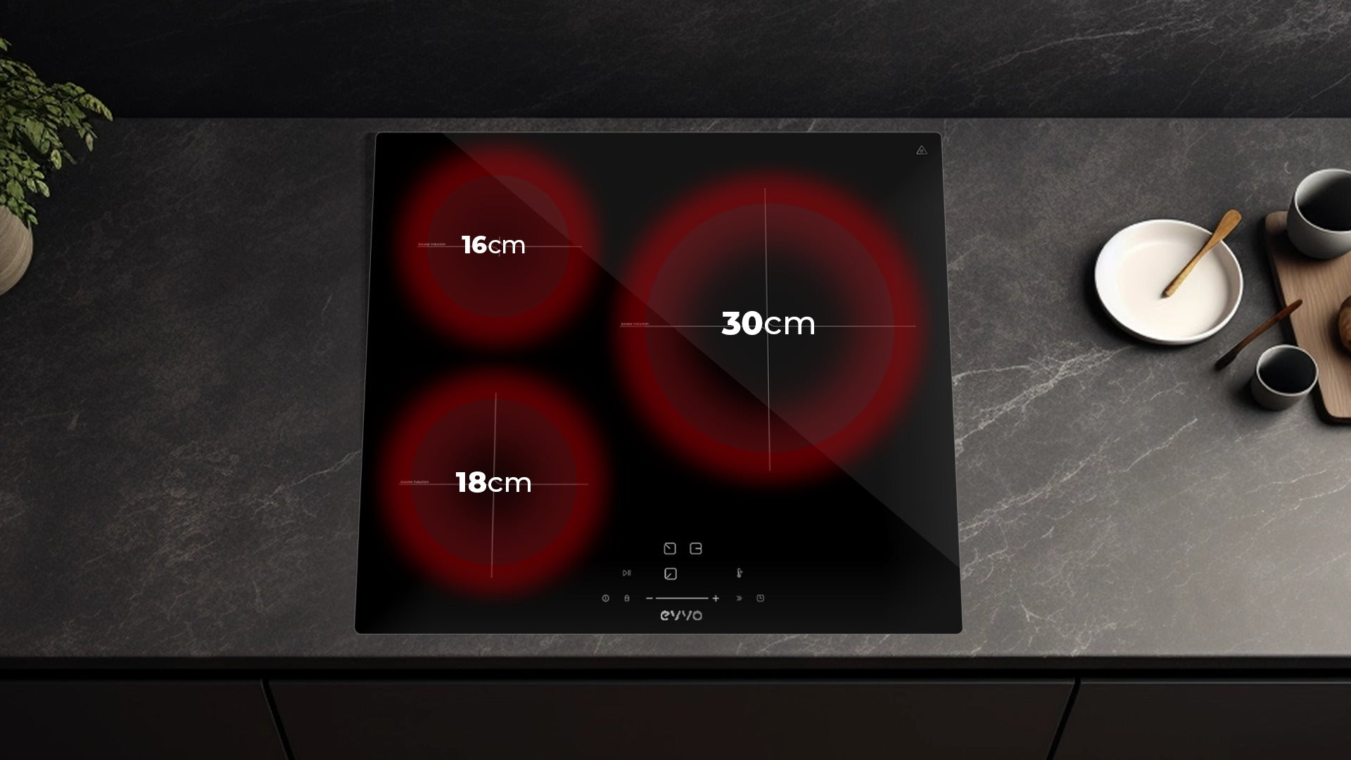 Placa de inducción negra con tres zonas de cocción rojas y medidas en cm sobre una encimera oscura.
