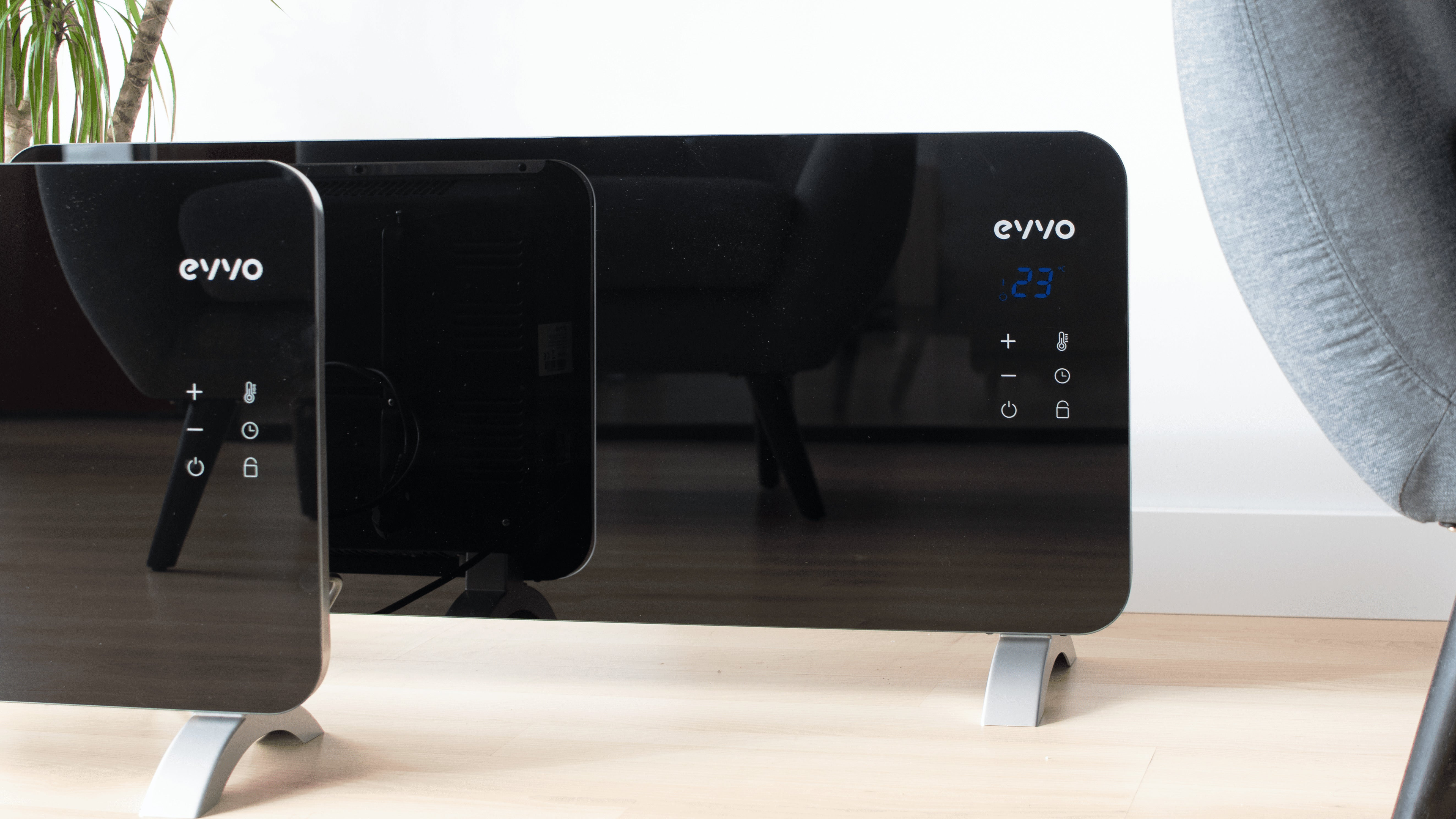 Un calefactor de convector eléctrico de vidrio negro con pantalla digital y controles táctiles en suelo de madera.