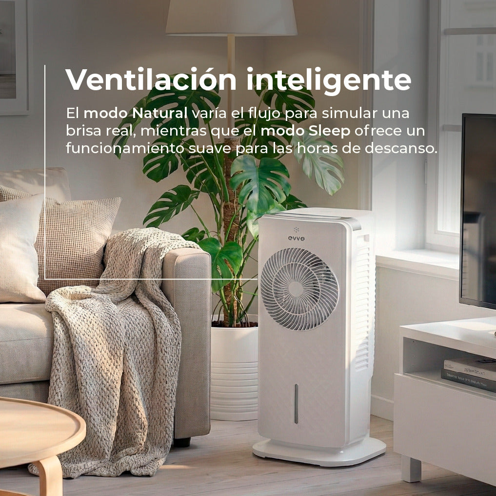 Un ventilador de torre blanco en la sala junto a un sofá con manta y una planta.