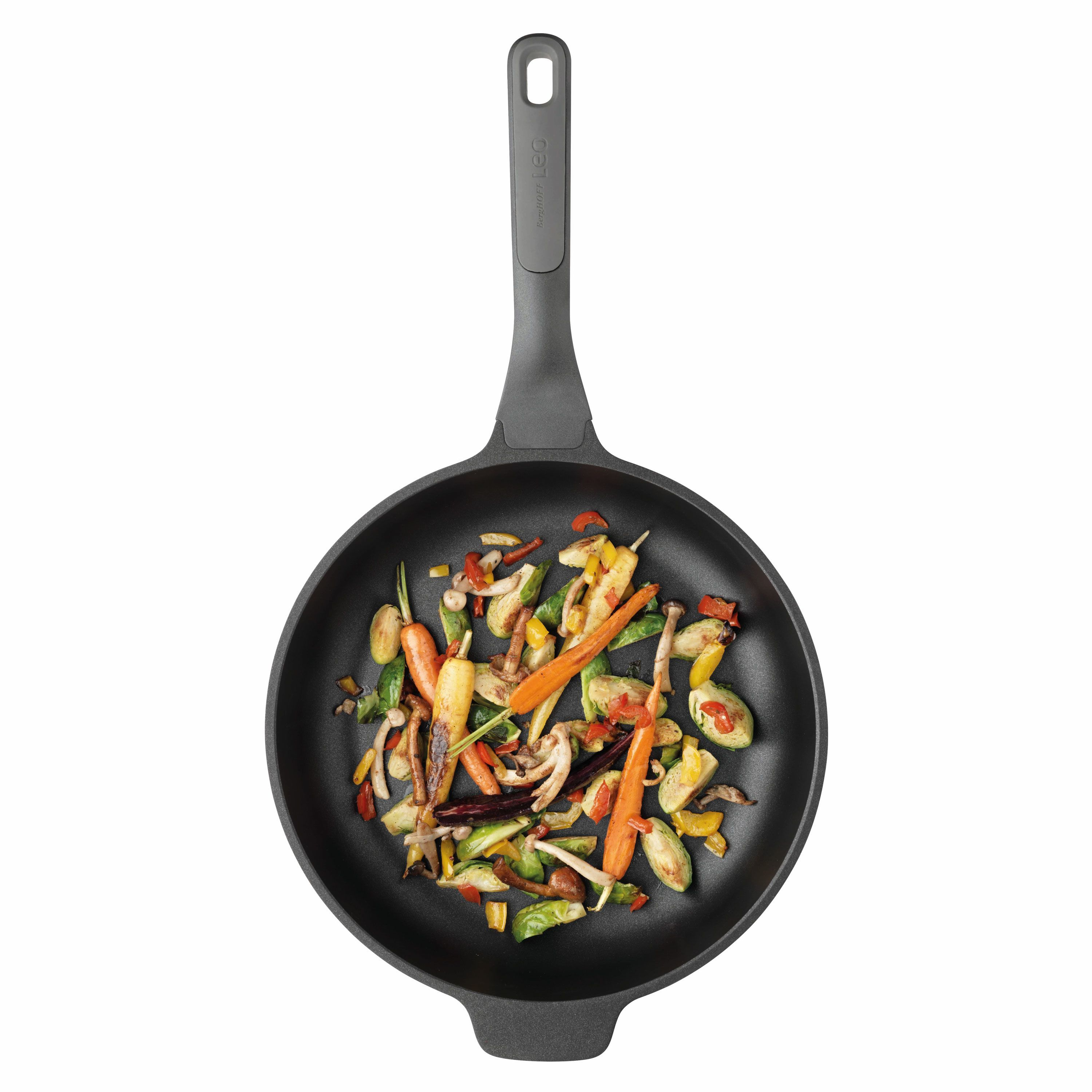 Vista cenital de una sartén negra con verduras asadas como zanahorias, coles de Bruselas y champiñones.