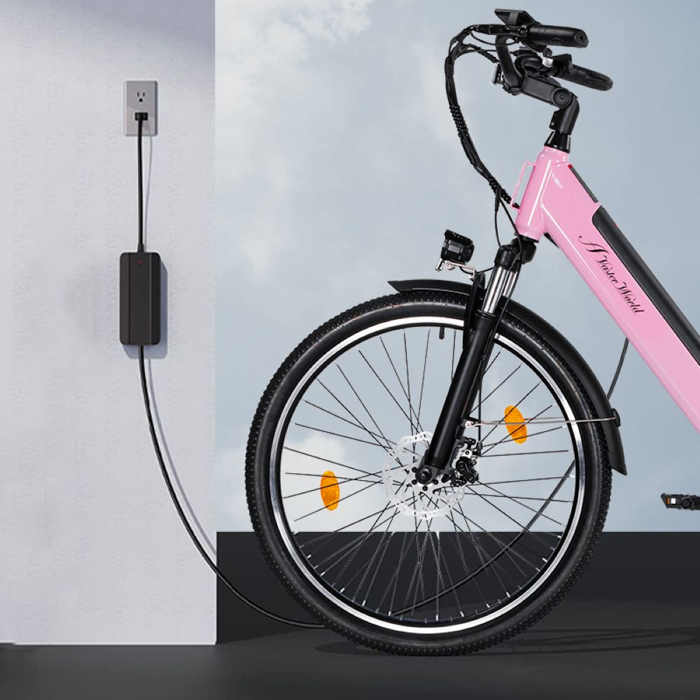 Una bicicleta eléctrica rosa conectada a un enchufe de pared con un cable negro.