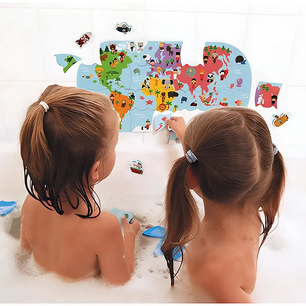 Zwei kleine Mädchen in einer weißen Badewanne spielen mit einem Schaumstoff-Weltkartenpuzzle.