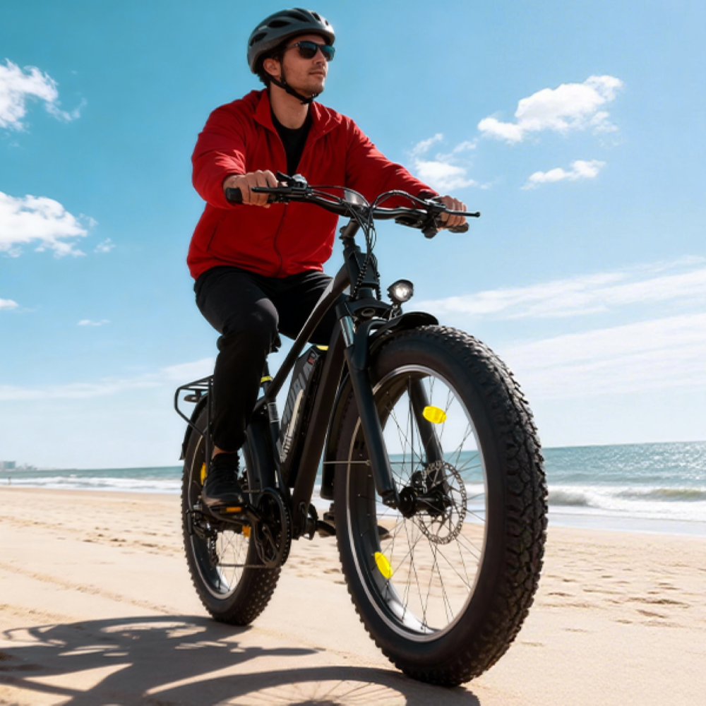 Un hombre con casco y chaqueta roja monta en bicicleta de rueda ancha por la playa.