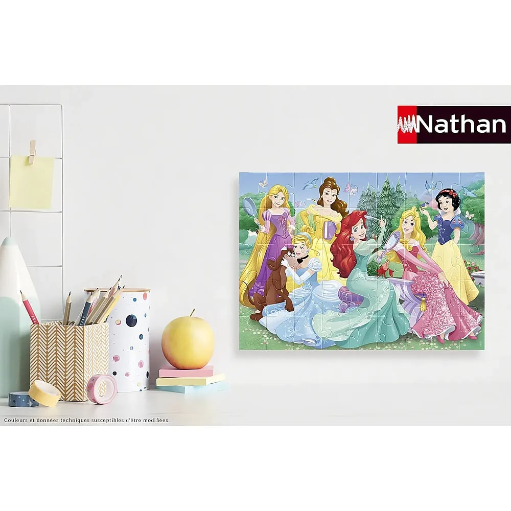 Ein Disney-Prinzessinnen-Puzzle an einer weißen Wand über einem Schreibtisch mit Stiften und einem Apfel.