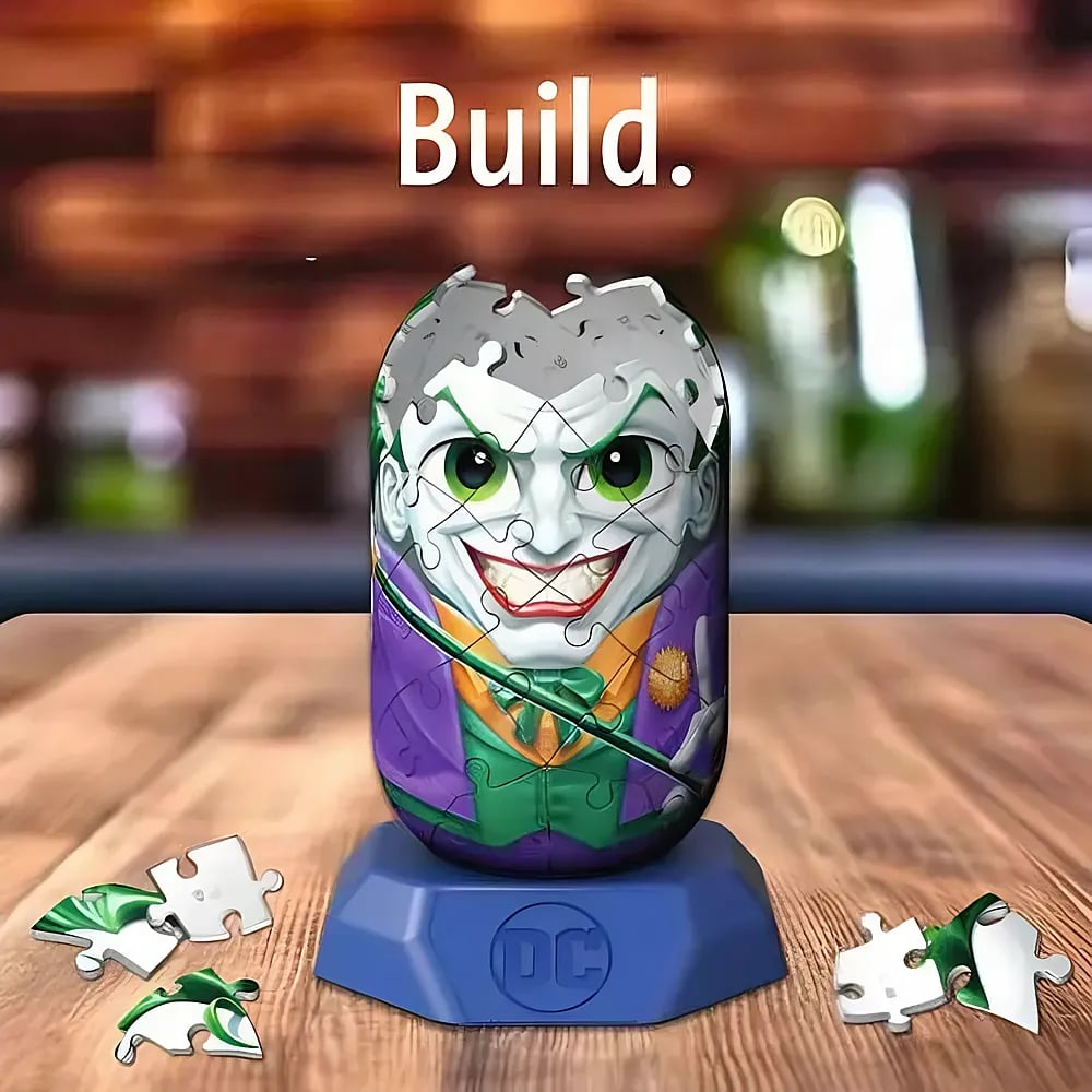 Ein Joker-3D-Puzzle auf einem DC-Ständer auf Holztisch, mit losen Puzzleteilen und dem Schriftzug "Build.".