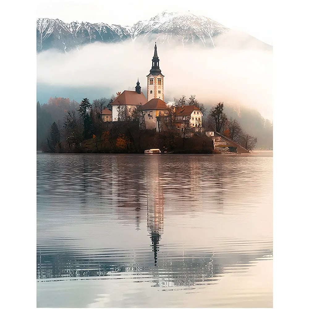 Eine Insel mit einer Kirche auf einem ruhigen See vor schneebedeckten Bergen und Nebel.