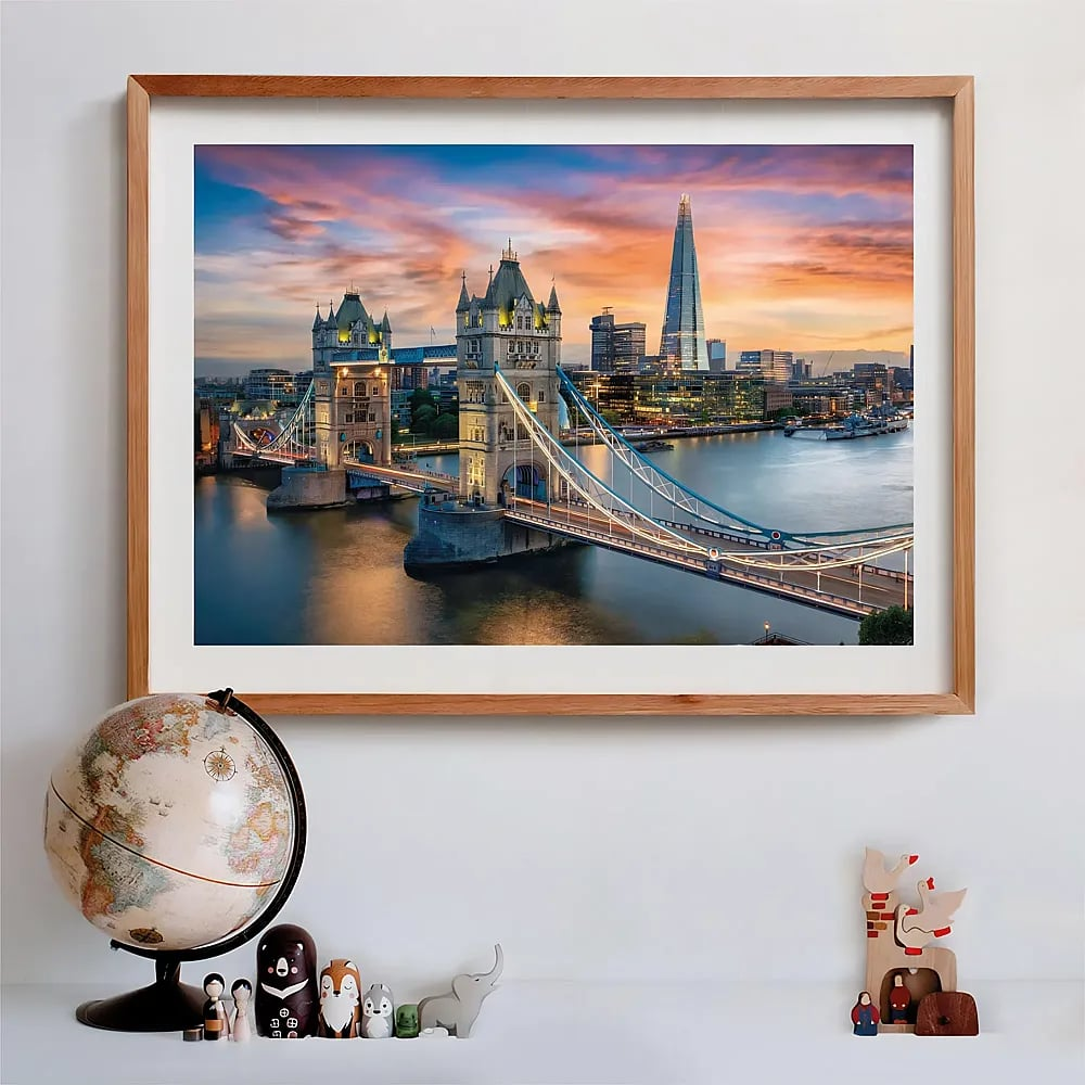 Een houten lijst toont Londen met de Tower Bridge bij zonsondergang, met een kleine wereldbol en beeldjes eronder.