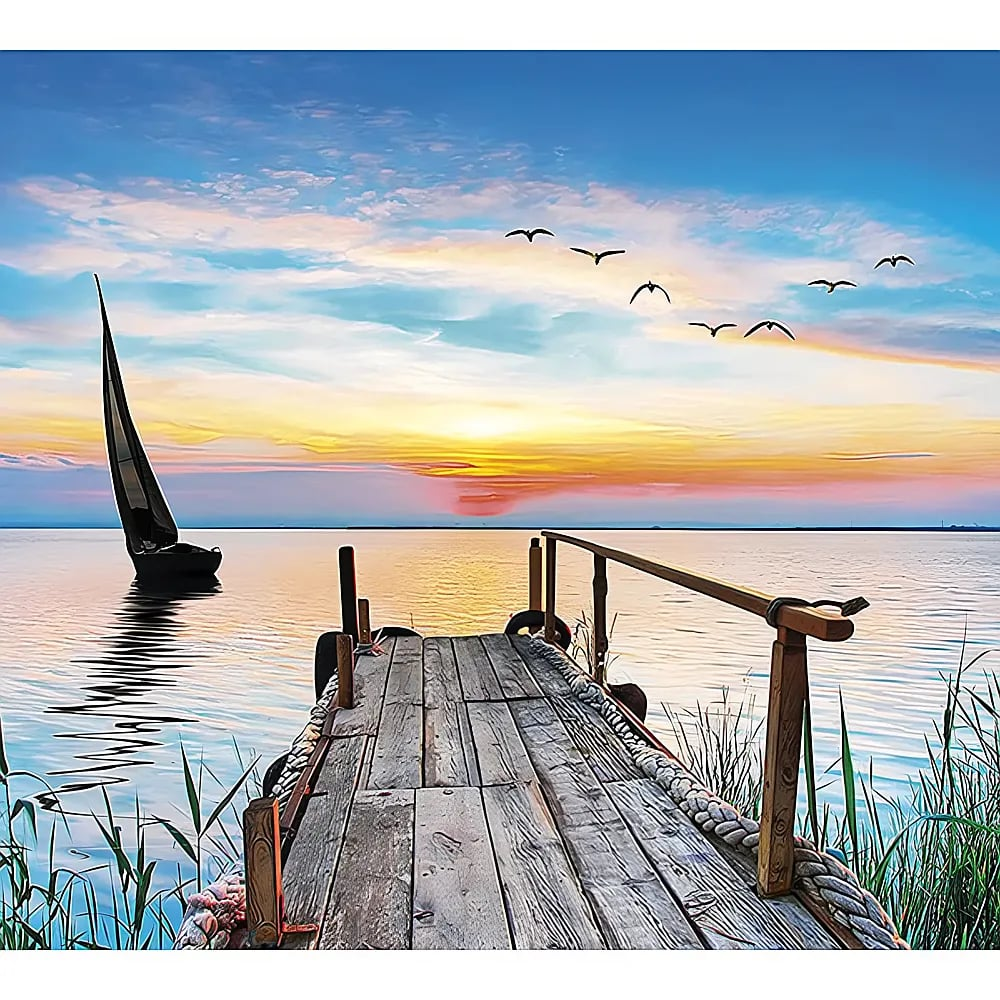 Ein Holzsteg führt in ruhiges Wasser, im Hintergrund segelt ein Boot und Vögel fliegen am Sonnenuntergangshimmel.