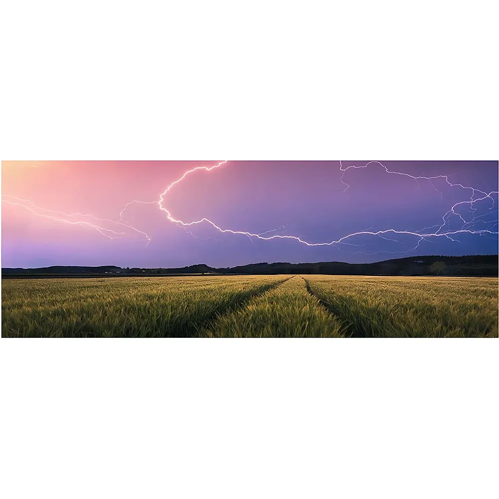 Ein Blitz leuchtet über einem grünen Feld mit fernen Hügeln bei Sonnenuntergang.