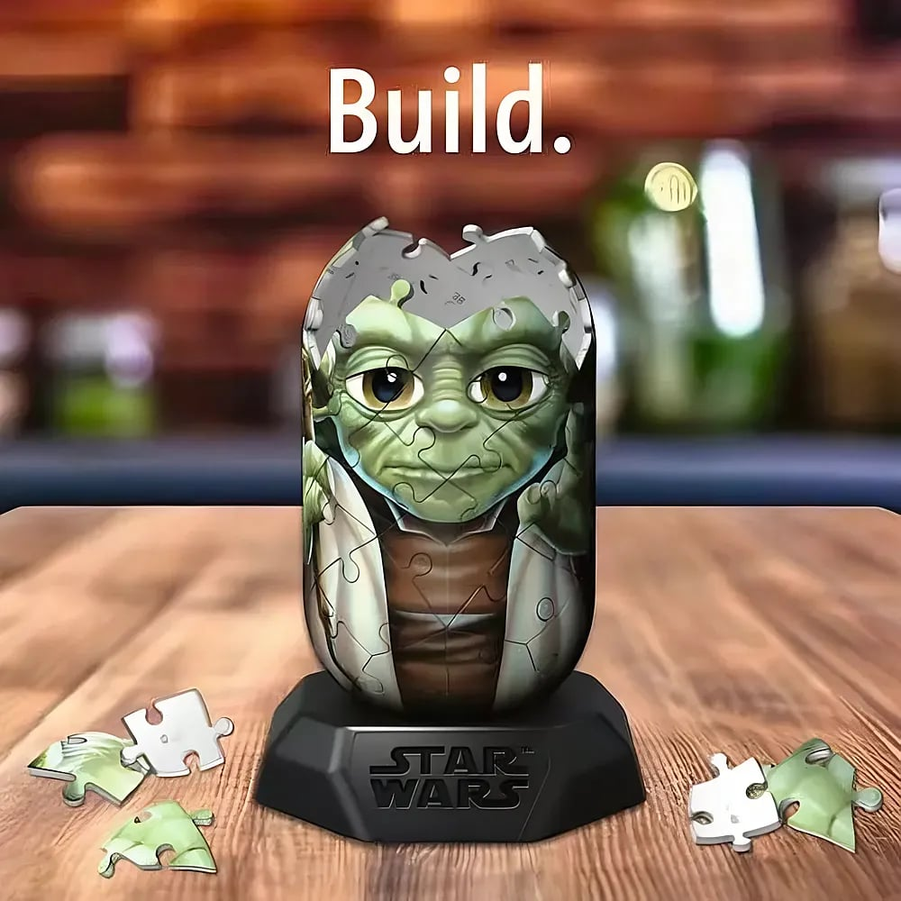 Ein 3D-Yoda-Puzzle steht auf einem Star-Wars-Sockel auf einem Holztisch, umgeben von losen Puzzleteilen.