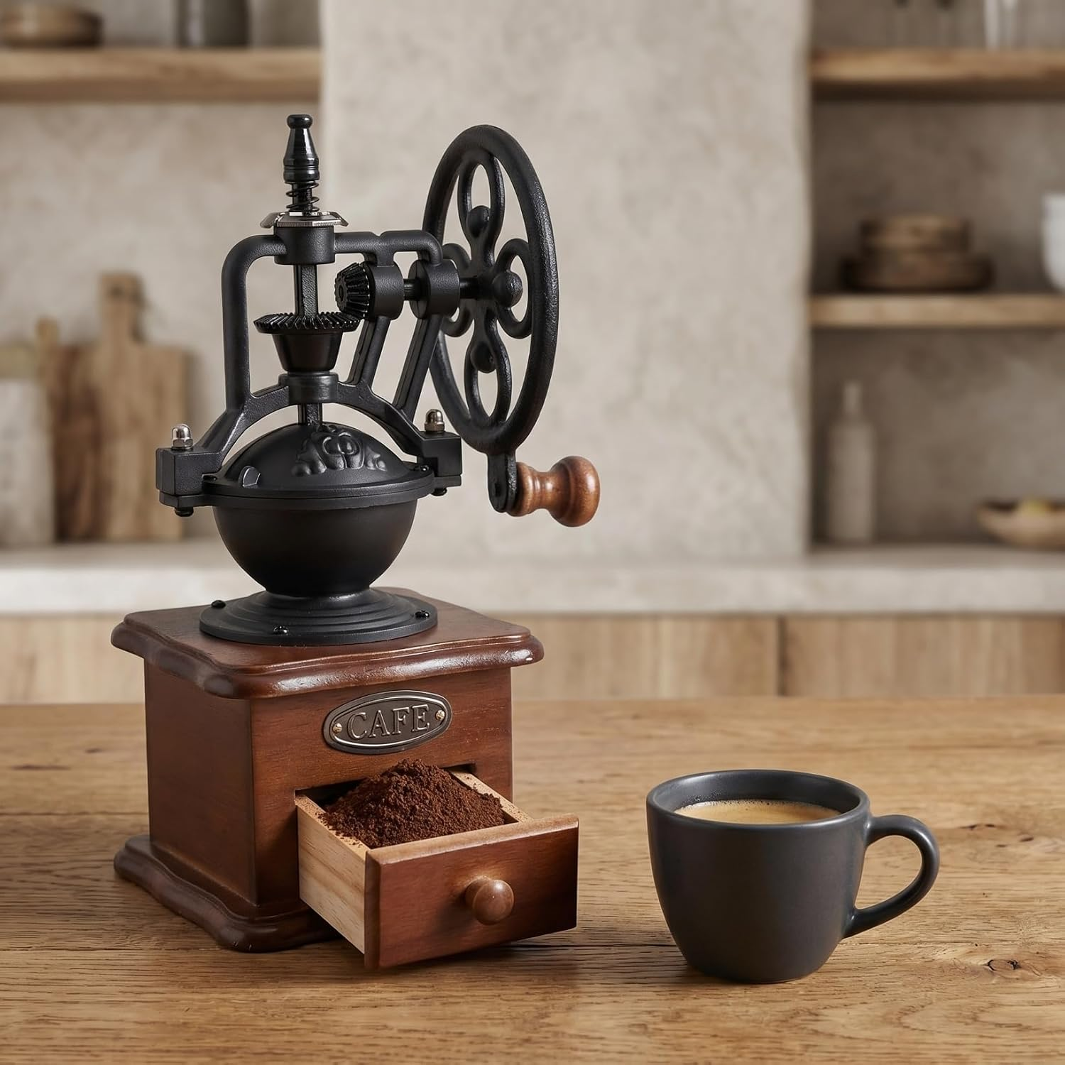 Eine alte Kaffeemühle aus Holz und Metall steht auf einem Tisch neben einer Tasse Kaffee.