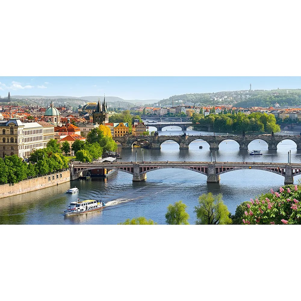Blick auf Prag mit der Moldau, historischen Brücken, Booten und Altstadtbauten im Hintergrund.