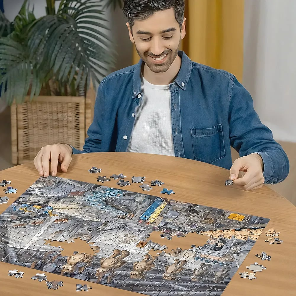 Ein lächelnder Mann im blauen Hemd sitzt an einem Holztisch und setzt ein großes Puzzle zusammen.
