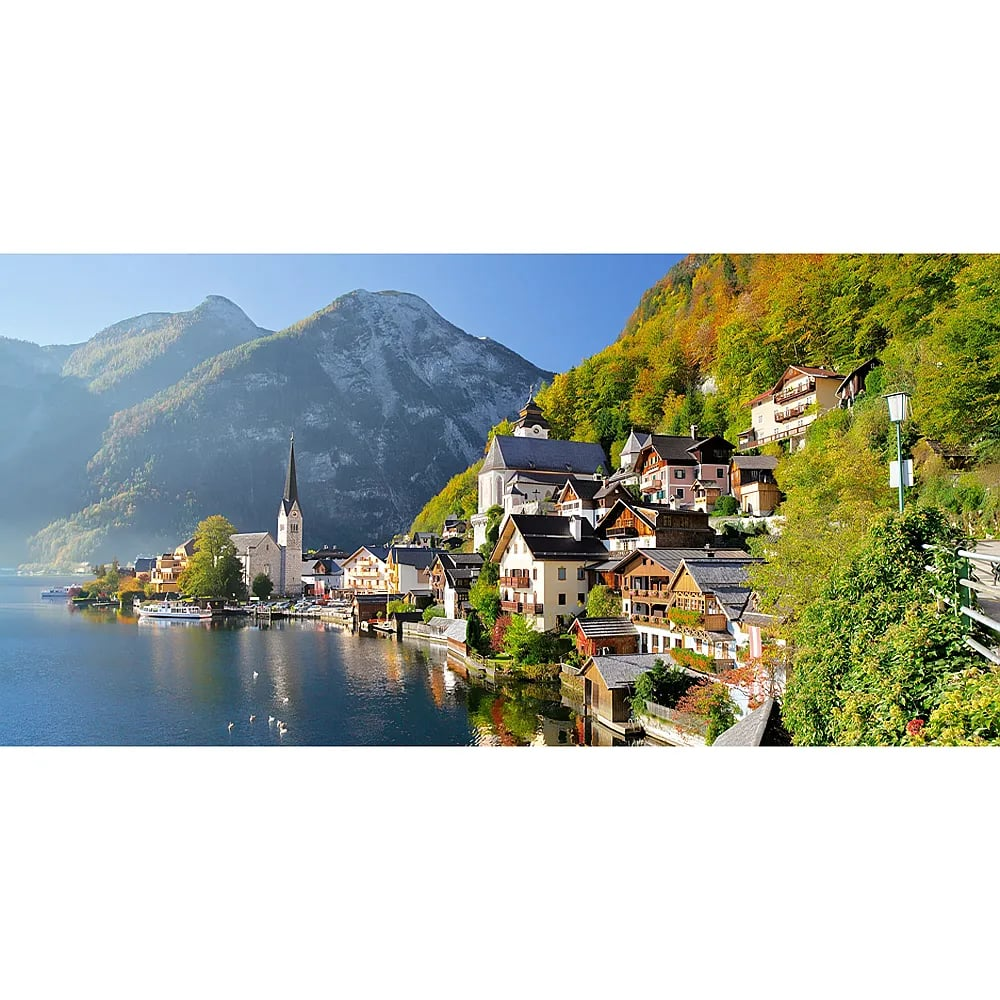 Das Dorf Hallstatt an einem ruhigen See mit hohen Bergen im Hintergrund unter blauem Himmel.