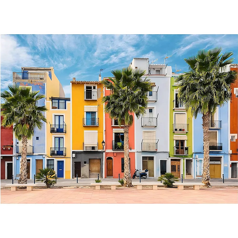 Bunte Gebäude und Palmen an einer Strandpromenade unter blauem Himmel.