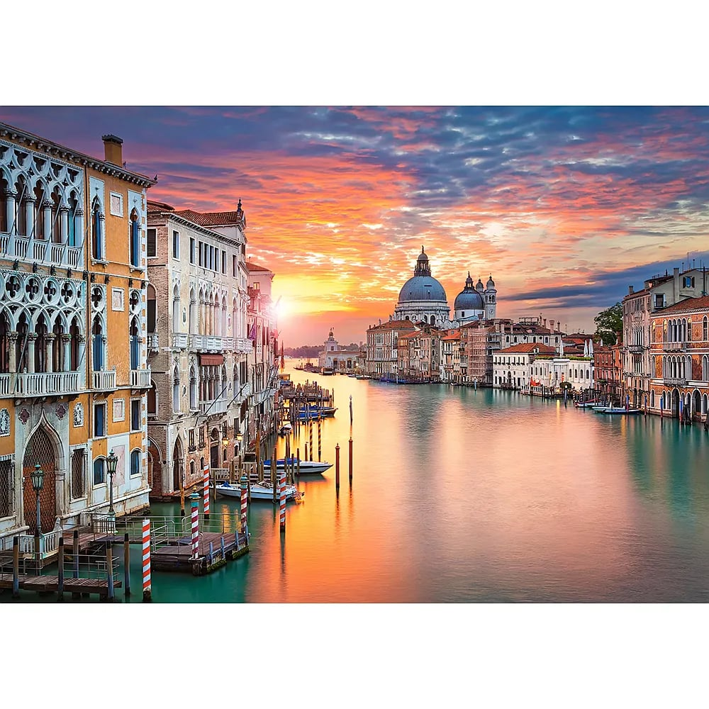 Grand Canal de Venise au coucher du soleil avec un ciel coloré se reflétant sur l'eau.