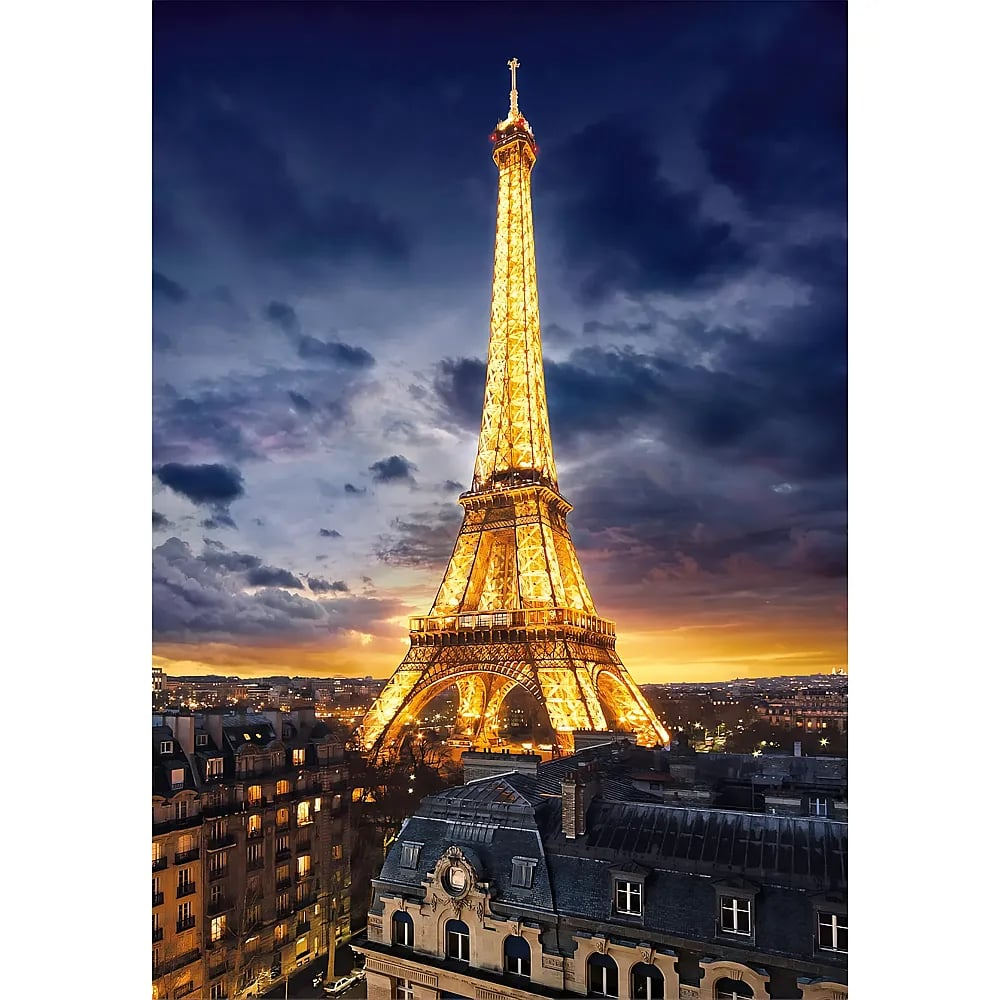 Beleuchteter Eiffelturm in Paris bei Nacht über Gebäuden.