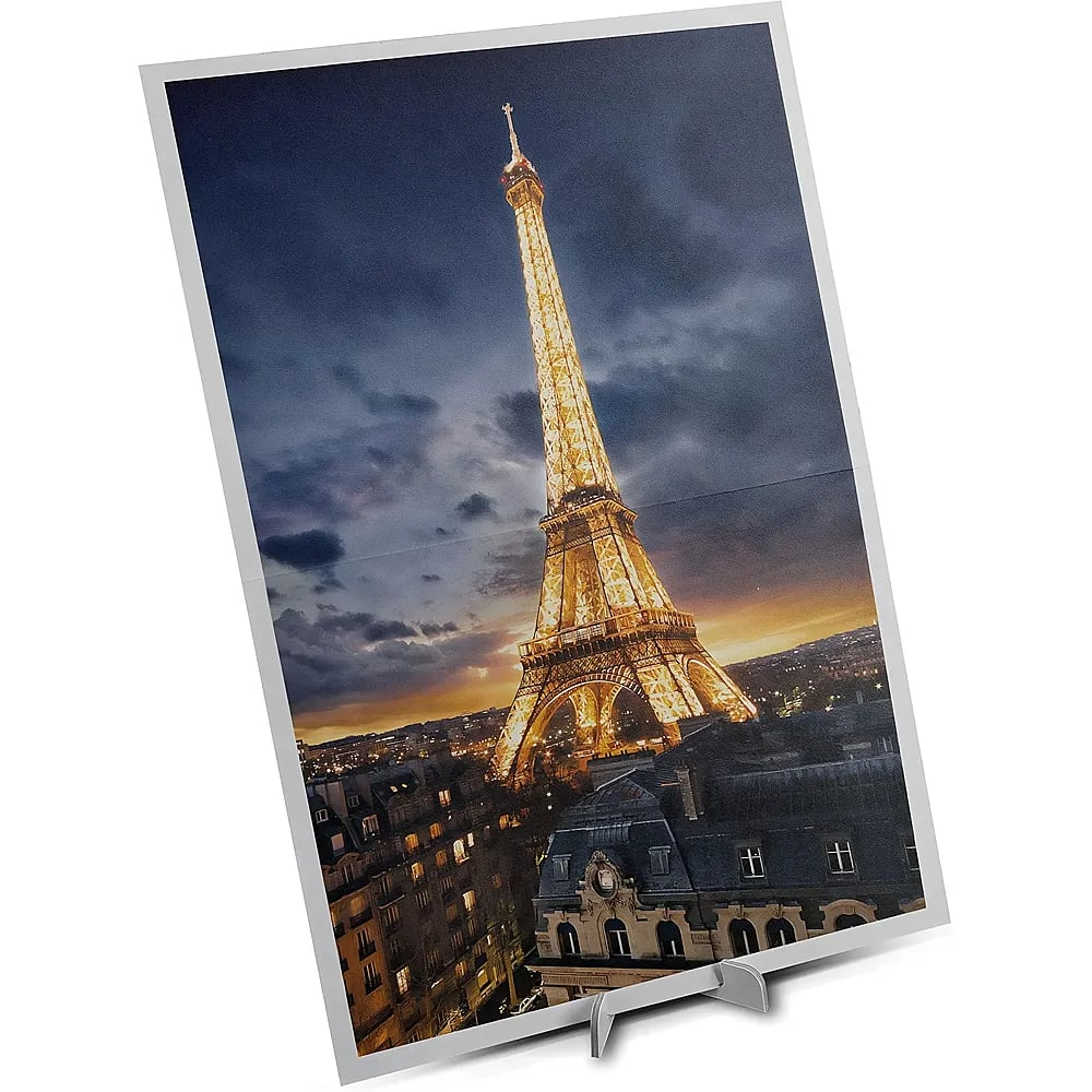 Ein gerahmtes Foto des beleuchteten Eiffelturms in Paris bei Nacht, auf einem Ständer.