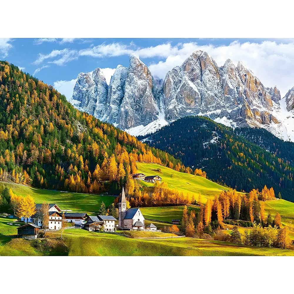 Un village de montagne pittoresque devant une chaîne de montagnes enneigée avec des arbres jaunes et une vallée.