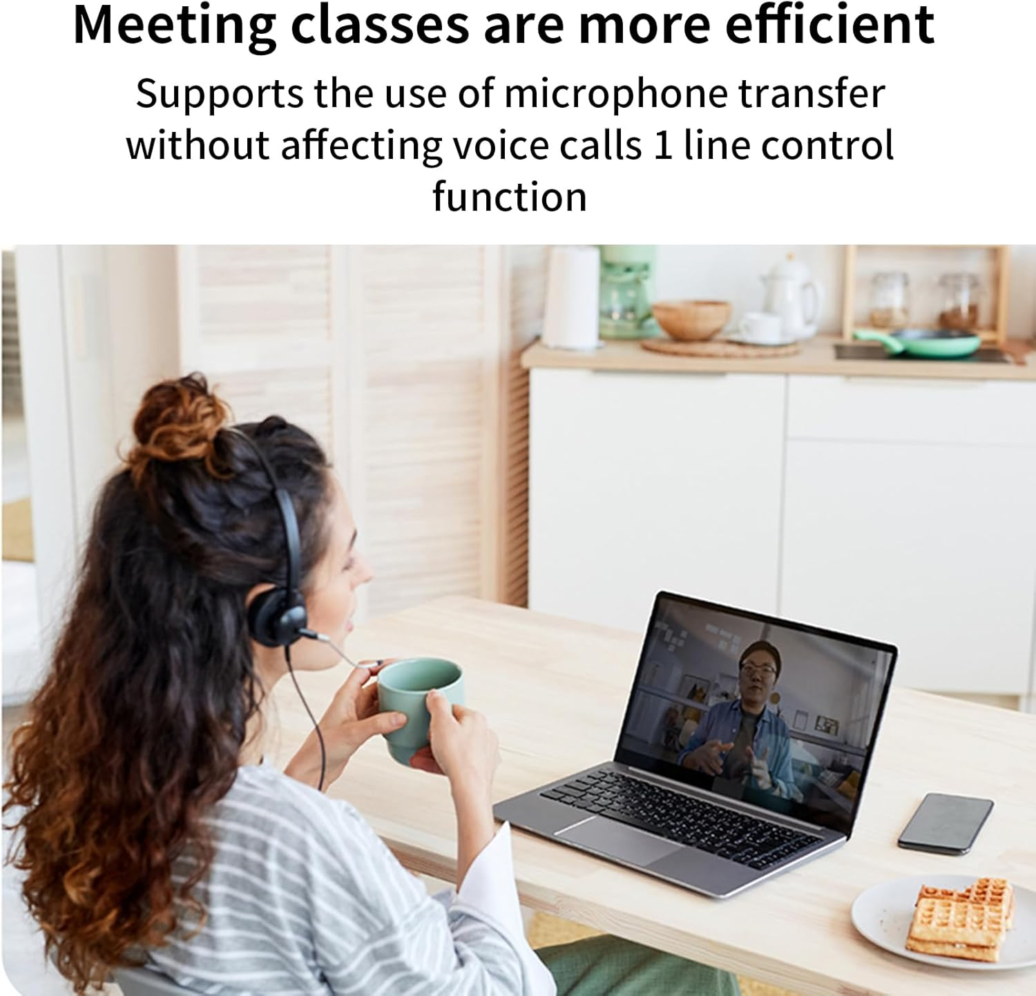 Frau mit Headset und Tasse trinkend nimmt an einem Videoanruf auf dem Laptop teil, im Hintergrund Küche.
