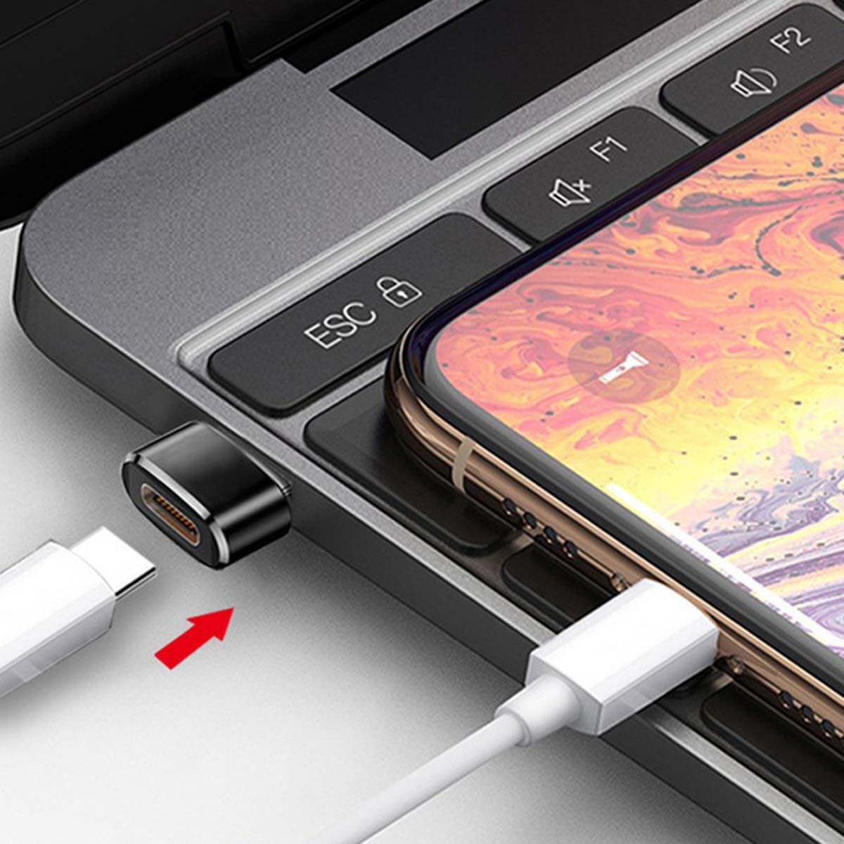 Ein USB-C-Kabel, ein kleiner Adapter und ein Smartphone auf einer Laptoptastatur.