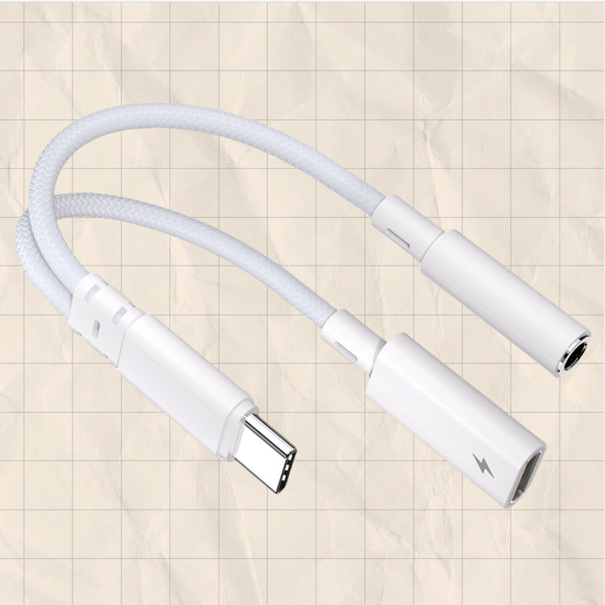 Weißes USB-C zu Klinke und Ladeadapterkabel auf kariertem Papier.