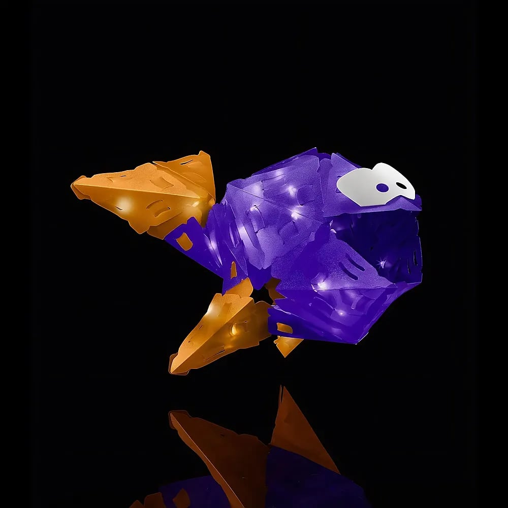 Eine leuchtende, violette und orangefarbene geometrische Papierfisch-Skulptur vor dunklem, reflektierendem Hintergrund.