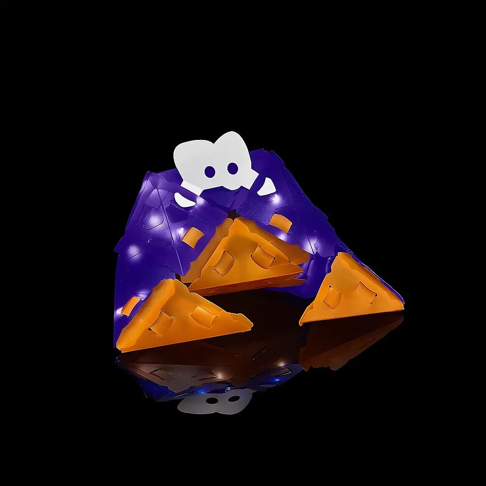 Eine violette und orangefarbene Pyramide aus Kunststoff mit einer weißen Figur an der Spitze auf schwarzem Hintergrund.