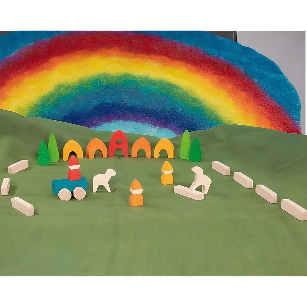 Bunte Holzspielzeuge stehen auf grünem Tuch vor einem bunten Regenbogen-Hintergrund.