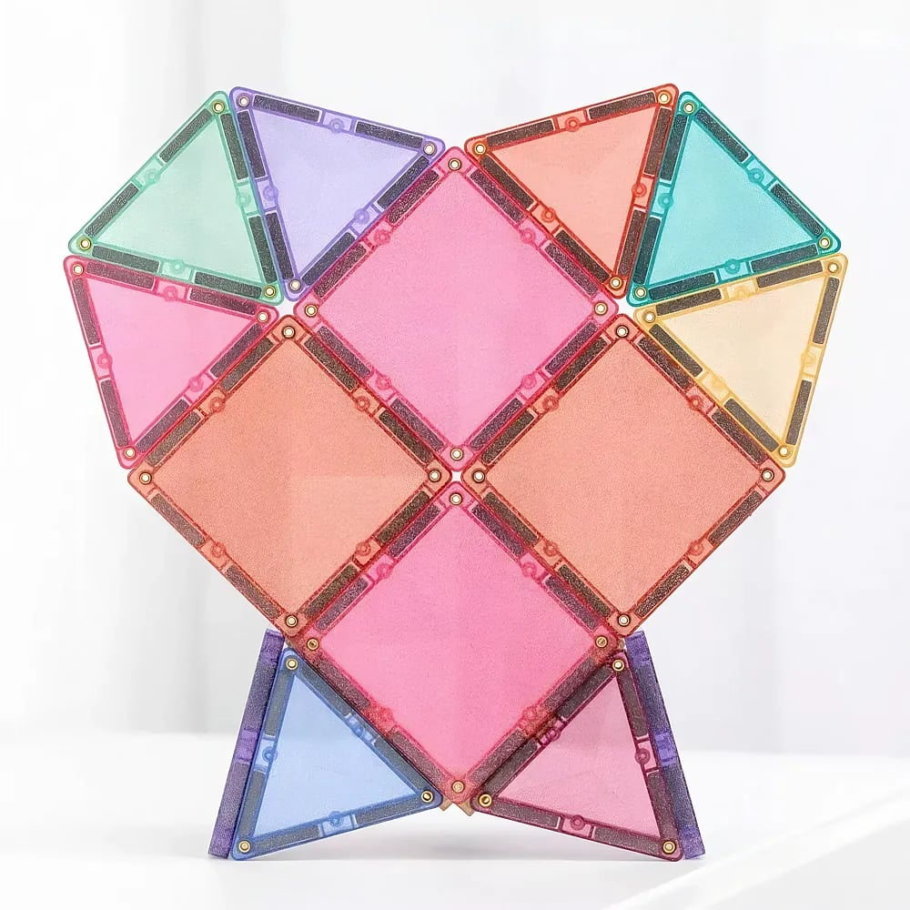 Struttura a cuore in piastrelle magnetiche colorate su superficie bianca con sfondo luminoso sfocato.