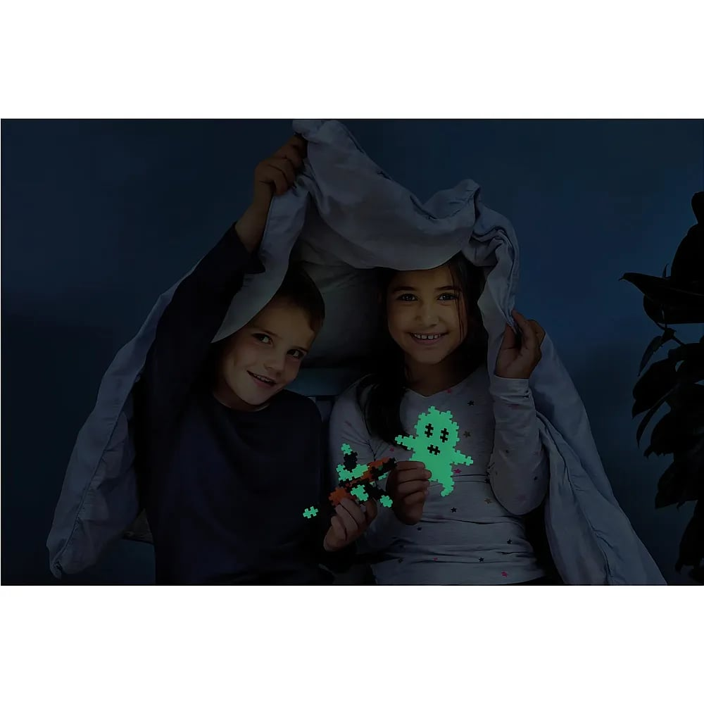 Ein Junge und ein Mädchen sitzen unter einer Decke und halten leuchtendes Spielzeug.